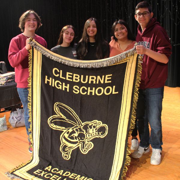  students holding up black and gold afghan
